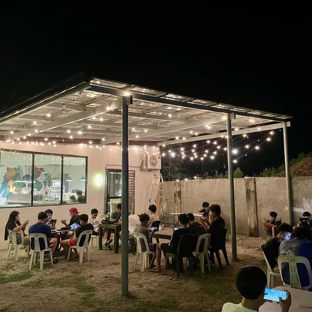 The alfresco area at night under string lights, full of guests