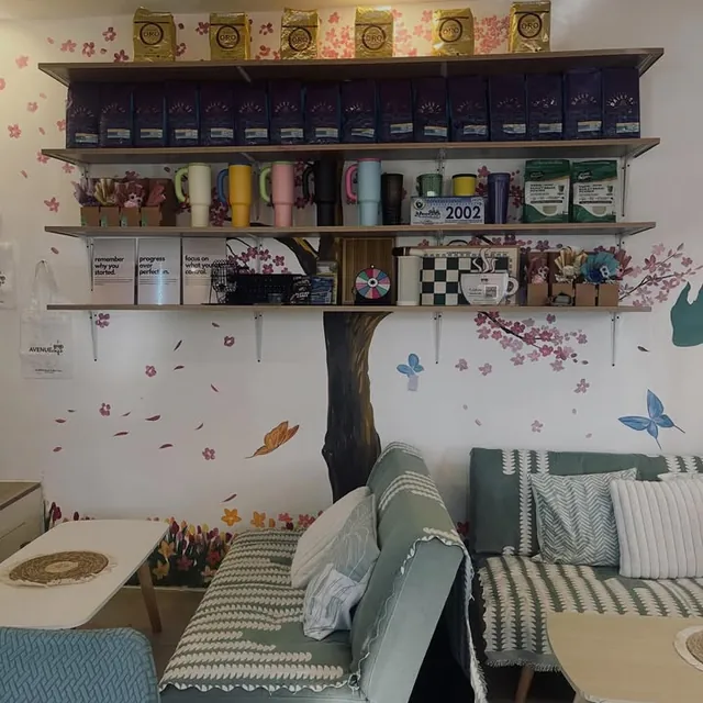 Sofas under a painted cherry blossom tree, with shelves of coffee bags and tumblers