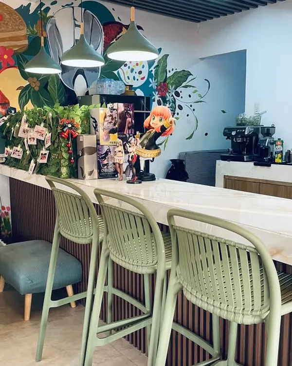 Green bar stools along the marble counter under pendant lamps