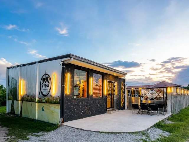 A’venue Café’s container building at dusk with warm amber light strips